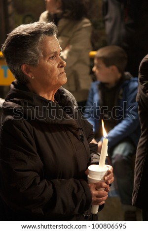 TORREVIEJA, SPAIN - APRIL, 02 : A woman prays holding a candle during Holy Week on April 2,2012 in Torrevieja, Spain. Tradition hundreds of years, typical in Spain.