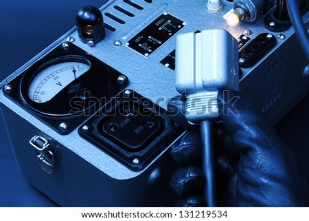 Electrician hand in black glove connecting a big plug to a vintage power generator on black background