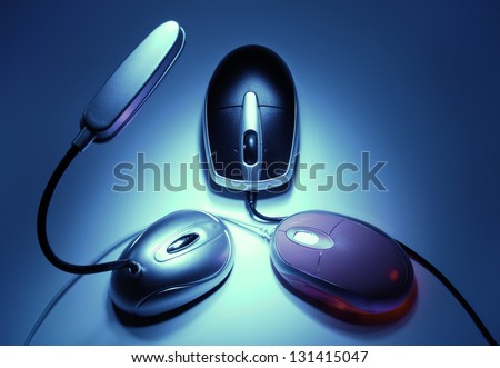 Artistic concept of symmetrical arrangement including portable lamp and two computer mice in the darkness (meeting)