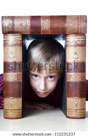 Happy cute blond boy in looking out from a window made of a stack of very old big books smiling (isolated on white background)
