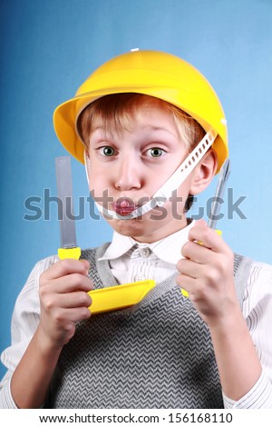 Beautiful cheerful blond boy as a construction worker wearing a yellow hard hat and colorful tools