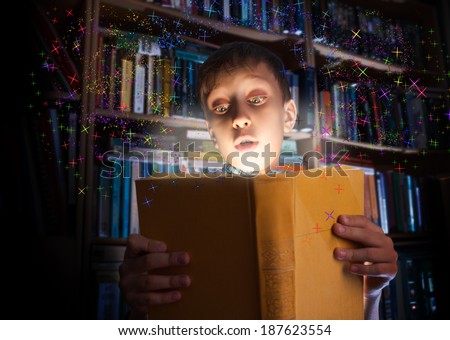 Beautiful funny child holding a big book with magical light looking amazed. Learning concept.