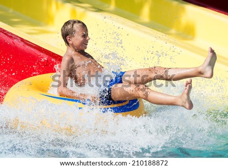 Funny child taking a fast water ride on a float splashing water. Summer vacation concept.