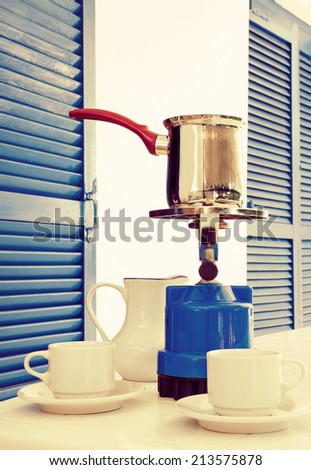 Coffee pot on a primus stove with cups and jug on summer veranda. Coffee concept.