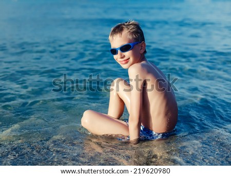 Funny little boy playing in sea smiling. Summer break concept.