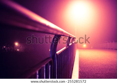 Romantic night city walk on a bridge in fog with street lights (toned).