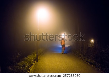 Night foggy ride on bike with street lights (diffused, toned). Sports concept.