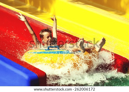 Funny child playing in water park splashing water. Summer holidays concept.