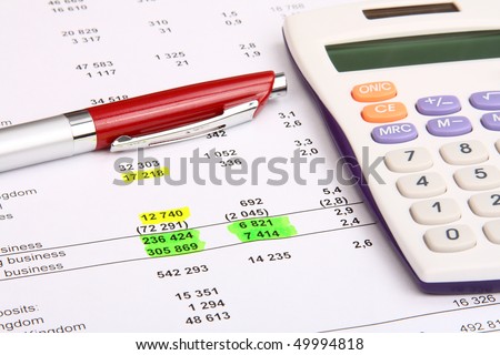 White calculator and a red pen on a financial report