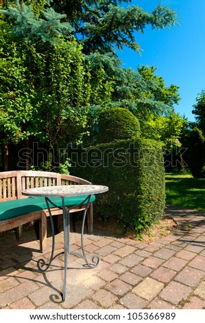 Garden table and bank and a trimmed hedge in garden