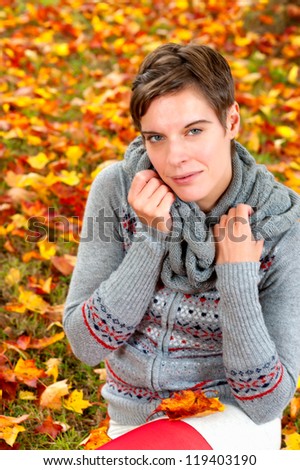 Young attractive woman, dressed in mini skirt, sitting in autumnal foliage enjoying the fall
