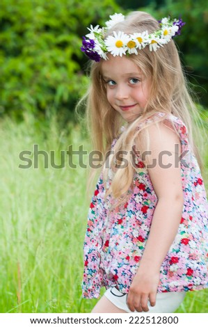 Cute happy little girl with a flower wreath at Midsummer