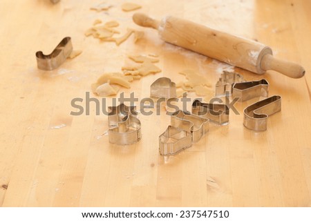 Rolling pin and different cake cutters, dough and  flour on a table, used for preparing christmas cookies and ginger bread