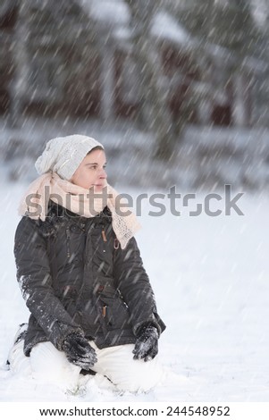 Woman kneeling in the snow and enjoy the fresh falling snow