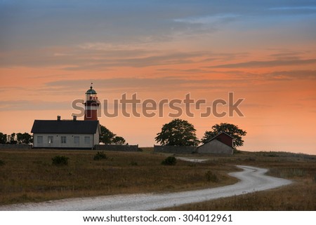 The lighthouse on the peninsula Naerholmen, Gotland, in the evening light. A dirt road leads to the lighthouse.