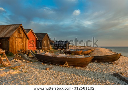 Fishing boats and fishing cabins on the stony beach of Faro, Sweden, in the light of the sunrise