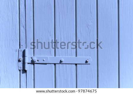 Detail of a blue painted wooden door with door hinge