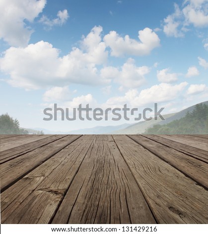 Wood Deck As A Tranquil Old Rustic Country Patio Floor In Perspective With A Summer Sky On A Beautiful Mountain Range With Forest Trees As A Symbol Of Travel And Backyard Living.
