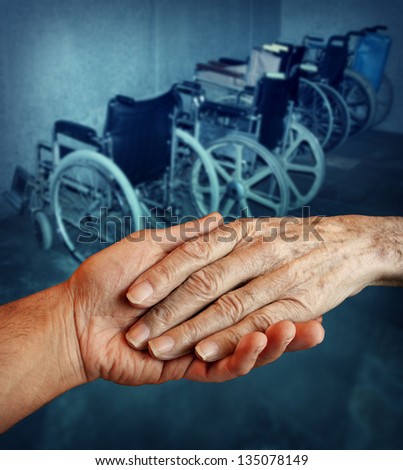 Disabled and Handicapped elderly medical health care concept with a young person holding and giving a helping hand to an old elderly grandparent with a group of wheelchairs in the background.