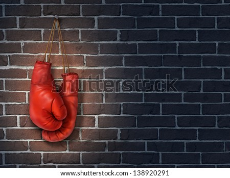 Stop competing and putting an end to business competition by hanging up a pair of red boxing gloves on a dark rustic old brick wall as a concept of stopping the fight to find the cure.