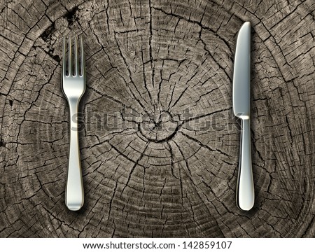 Natural food concept and organic eating healthy lifestyle idea with a silver fork and knife on a cut tree stump log representing raw food and rustic country cooking and traditional cuisine.