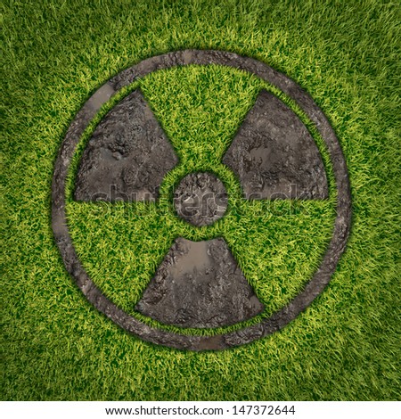 Contaminated soil concept with a green grass and the radio active symbol embossed in the ground exposing the poisoned earth as an icon of environmental disaster after a nuclear disaster fallout.