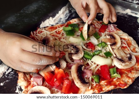 Child preparing pizza with the hands of a kid and fresh ingredients as mushrooms mozzarella cheese onions and dough as delicious food for dinner or learning how to cook at a culinary class.