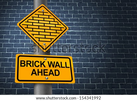 Against A Brick Wall business concept of hardship and difficult restrictions faced on a journey focused on success as a yellow traffic sign warning of a future challenging obstacle obstructing goals.
