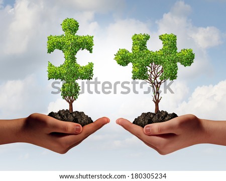 Collaborating together business concept with two human hands holding trees shaped as a jigsaw puzzle coming together as a success metaphor for growing cooperation and to build a  teamwork agreement.