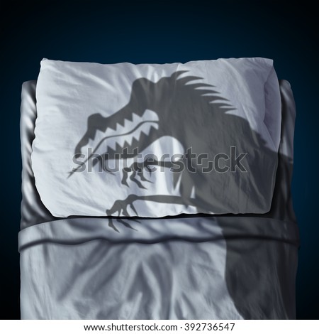 Nightmare and scary night dream concept as a cast shadow of a creepy monster on a bed with a pillow on a mattress as a symbol of childhood sleep anxiety or bedtime stress.