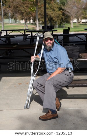 Older gentleman resting on a park bench while holding his crutches while wearing an insulin pump and contemplating his accident