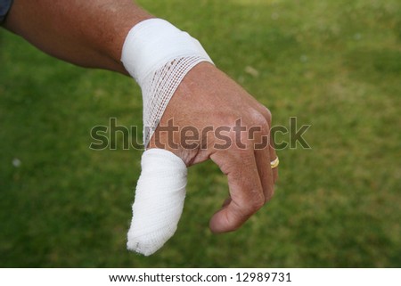  Hurt thumb with surgical dressing on the hand of an older man wearing