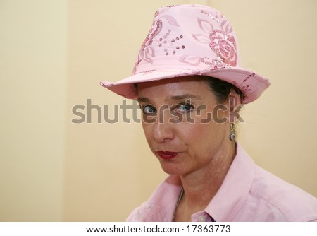Senior woman wearing a pink hat with a stern expression