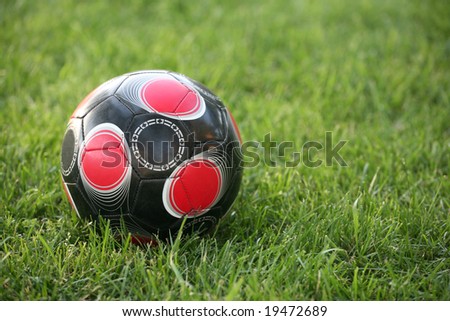 Black white and red soccer ball on a natural grass background