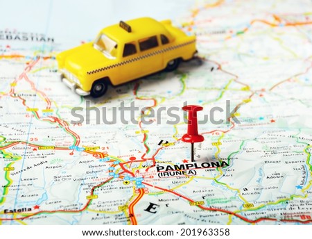 Red push pin pointing at Pamplona ,Spain  map and a taxi