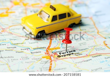 Close up of  Ferrara , Italy map with red pin  and a taxi  - Travel concept