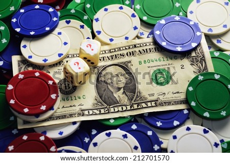 Dollar bill casino chips and dice hidden under  question mark- risk concept