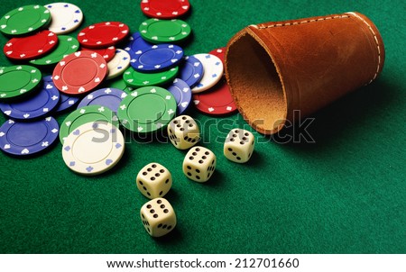 Five dice and a leather cup on green cloth- win concept