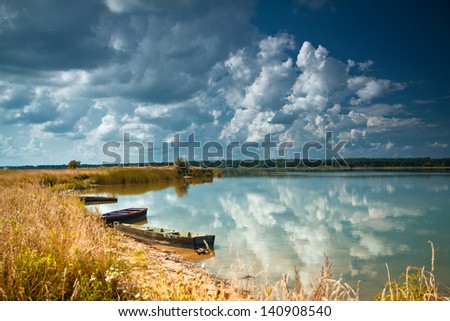 boat floating in the river amidst beautiful storm clouds
