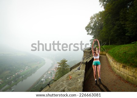 woman goes in for sports. Walks through Europe. autumn fog and the mountain with the castle.