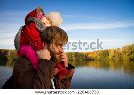 Dad and daughter. daughter fell asleep on his neck with his father in autumn park