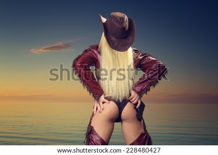sexy woman cowboy .sunset at sea. variety of colors and hues of the rising sun
