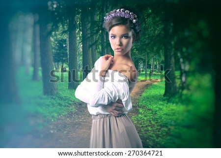 girl in the image of a forest fairy with flowers on her head standing in the woods on the road. Photo instagram style. vintage retro