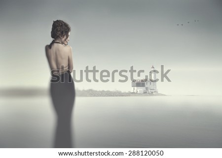Girl in evening dress standing on the beach in heavy fog and looking at the fog and flying birds. mysticism