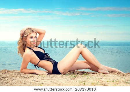 sexy blonde woman on a sunny summer day lying on the beach by the sea. Vacation.