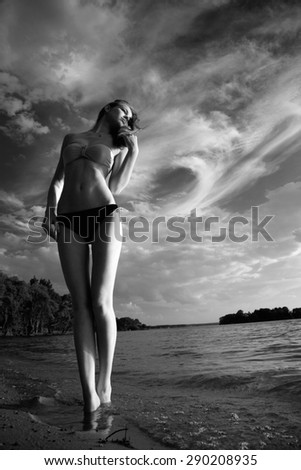 black - white photo. beautiful sexy woman in a swimsuit on the sea coast in summer evening. the trees on the ocean