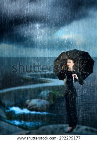 beautiful girl sitting on the bank of the dam at the sea during a storm under the umbrella. lightning comes rain