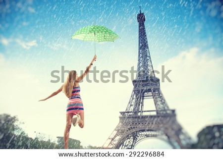 Beautiful girl running with an umbrella in the rain on a background of the Eiffel Tower. Summer trip to France in Paris.