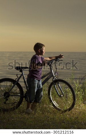 young boy with a bicycle in nature rests. summer vacation