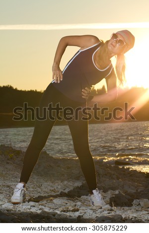 Fitness sport model doing exercises during outdoor work out on sunrise. Beautiful caucasian female training outside on seaside in the morning
